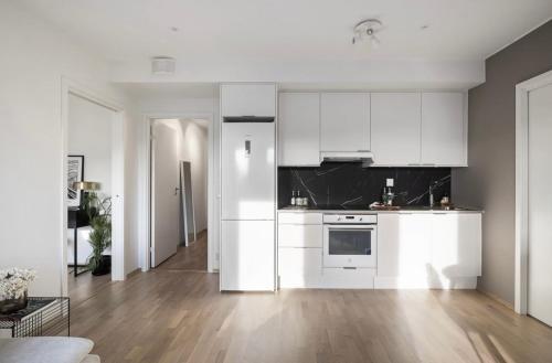 奥斯陆Private room in sharded apartment at Løren的白色的厨房配有白色橱柜和木地板