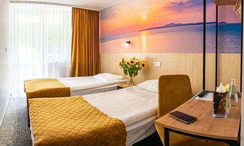 斯马德泽维采克弗兰诺热克雷西莫洛中央酒店的酒店客房,设有两张床和一张鲜花桌。