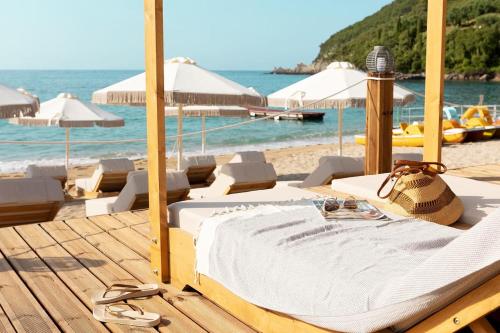 帕尔加享受里克诺斯湾村庄营地公寓式酒店的海滩上的一张床铺,配有椅子和遮阳伞