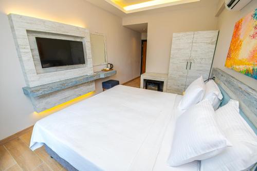 达特恰Feri Surf Club Hotel Datça的卧室配有白色的床和平面电视。