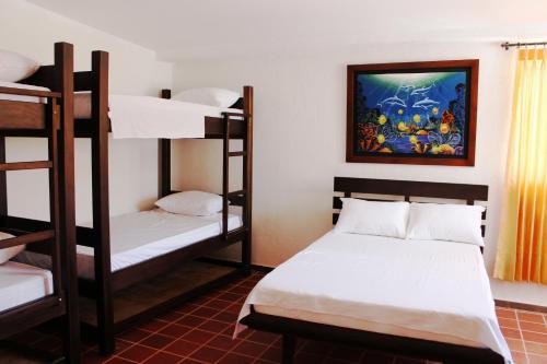 塔甘加Hotel San Marcos Taganga的客房设有两张双层床,墙上挂有绘画作品
