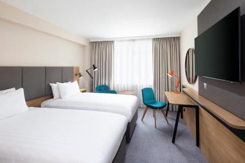 考文垂克文特日M6J2度假旅馆的酒店客房设有两张床、一张桌子和一台电视。