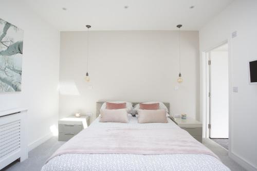 沃辛Oceans 12a Shelley Lofts, sleeps 4的白色卧室配有带粉红色枕头的大床