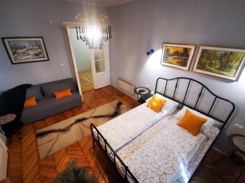 松博尔Sombor 19 Central Apartment的一间卧室配有带橙色枕头的床和沙发