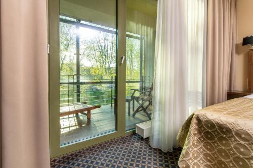 德鲁斯基宁凯德鲁斯金卡列图维Spa大酒店的客房设有一张床和一个阳台的玻璃门