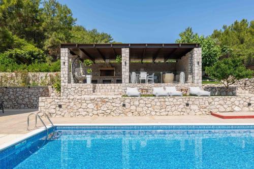 依克希亚Adonis Villa in nature的一座房子旁的游泳池,设有石墙