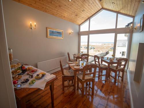 恩尼斯克朗Ceol na Mara Guest House的用餐室配有桌椅和食物