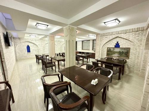 布哈拉Antique hotel Imran的一间在房间内配有桌椅的餐厅