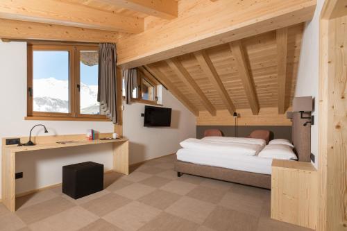利维尼奥Hotel Li Anta Rossa的一间卧室配有一张床、一张书桌和一个窗户。