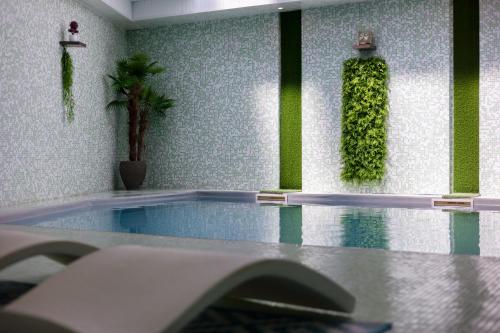 拉戈尔Hôtel et SPA du Château的一间房间,墙上设有一座种植了绿色植物的游泳池