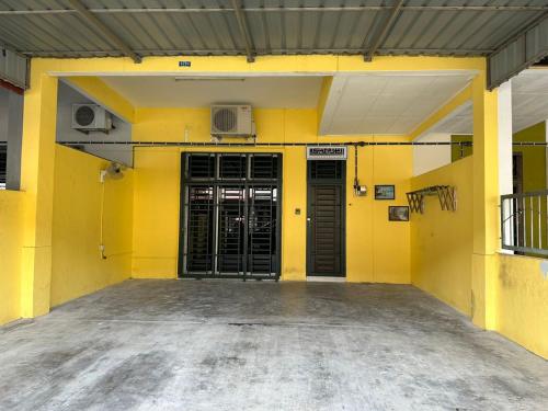 古来Naurah Homestay Kulai Mslim Only的黄色的建筑,有黑色的门和扬声器
