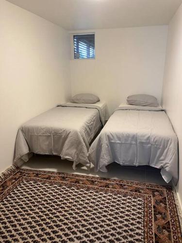 哥德堡Boende nära centrum och natur的白色客房的两张床,铺有地毯
