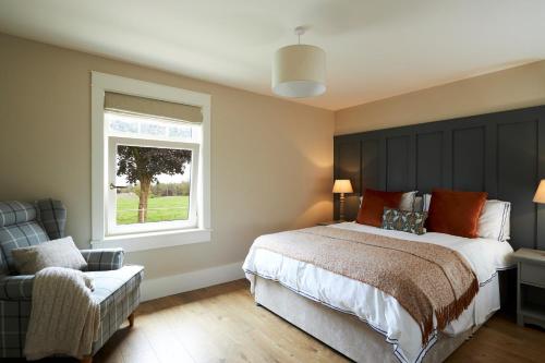 Raheen BridgeLovely home close to Killaloe and Lough Derg的一间卧室设有一张床、一个窗口和一把椅子