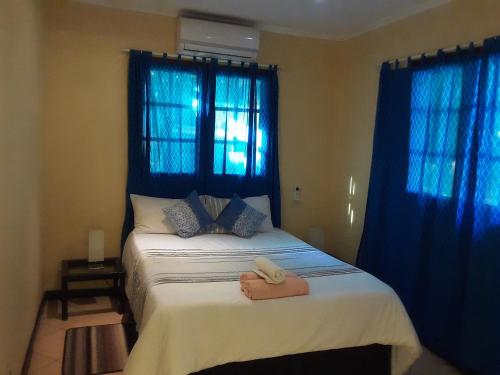 普拉伊拉多比莱尼Joao's Place的一间卧室配有一张带蓝色窗帘的大床