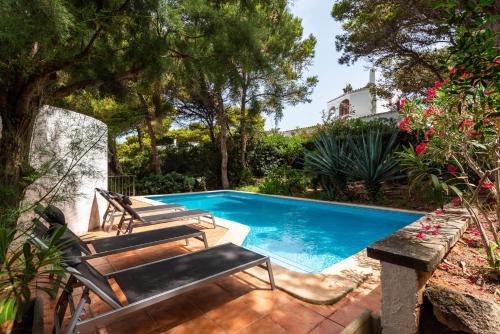 卡拉莫若尔Villa Menorca Ses Roques Vermelles by Mauter Villas的一个带长椅和树木的庭院内的游泳池
