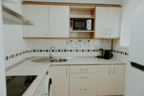 阿尔加罗沃Vimar Algarrobo Costa的白色的厨房配有水槽和微波炉