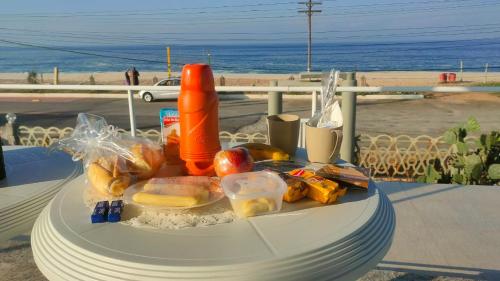 马里卡Suítes Pé Nareia Itaipuaçu的一张桌子上摆着的盘子,享有海滩美景