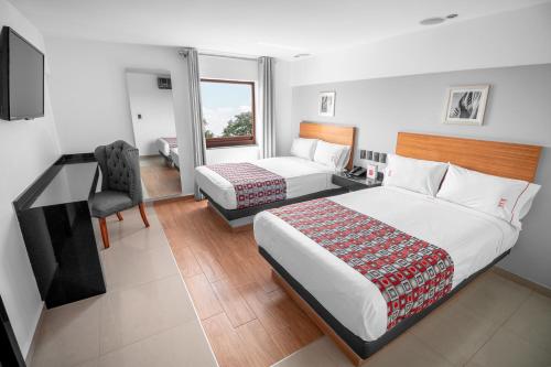 瓜达拉哈拉Six Hotel Guadalajara Expiatorio的一间卧室配有两张床、一张桌子和一把椅子