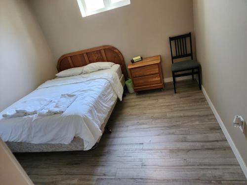 伯纳比Economical Homestay的一间卧室配有一张床和一把椅子,铺有木地板