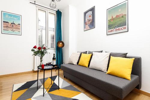 利布尔讷- Le P'tit nid -的客厅配有灰色的沙发和黄色的枕头。
