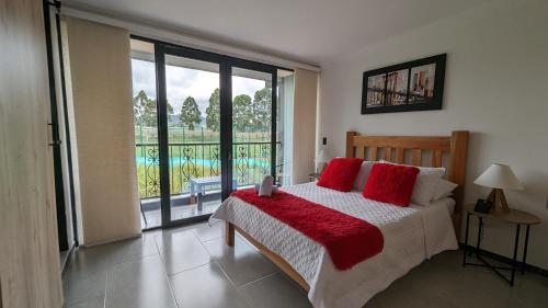 圣罗莎德卡瓦尔Apto lujo con jacuzzi y parqueadero piso 4的一间卧室配有一张带红色枕头的床和一扇窗户