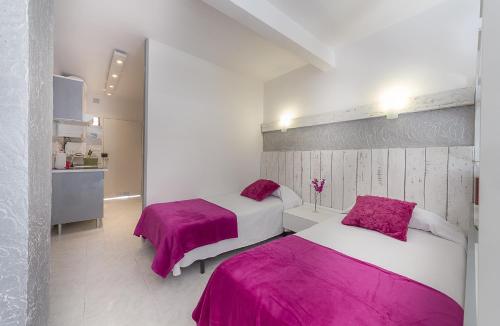 拉克鲁斯Seguro de Sol Studios的白色客房内的两张床和粉红色床单