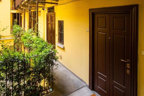 米兰Palm Apartment的黄色的建筑,有黑色的门和一些植物
