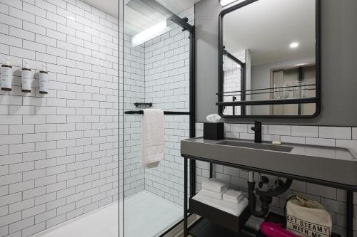 查尔斯顿Moxy Charleston Downtown的一间带水槽和玻璃淋浴的浴室