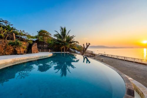 龙目岛库塔Inlight Lombok Beach Hotel的享有日落的水上游泳池