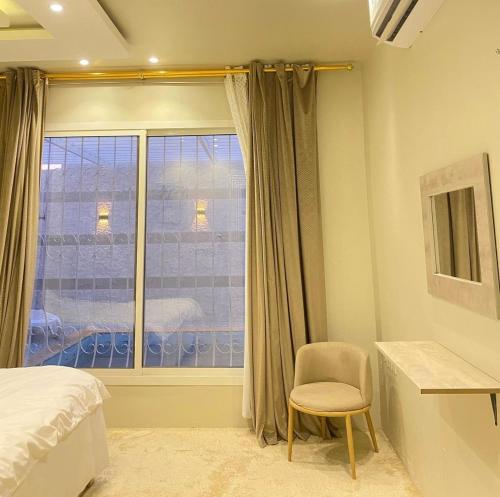 Al Liqāʼشاليهات لانتانا الفندقية的一间卧室设有一张床、一个窗口和一把椅子