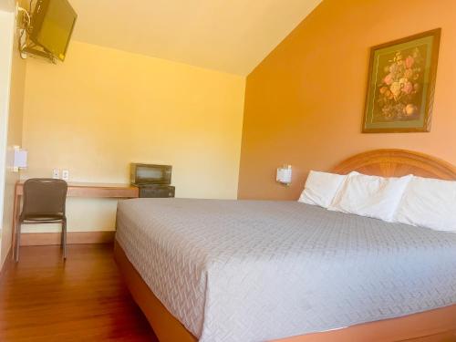 KingfisherPAYLESS INN的配有一张床和一把椅子的酒店客房