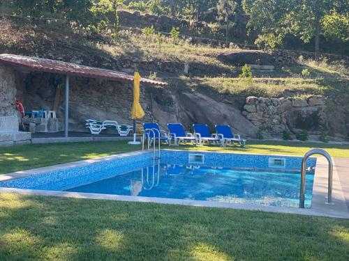 雷森迪Quintinha de Pinouco的一座房子旁的游泳池,配有蓝色的椅子