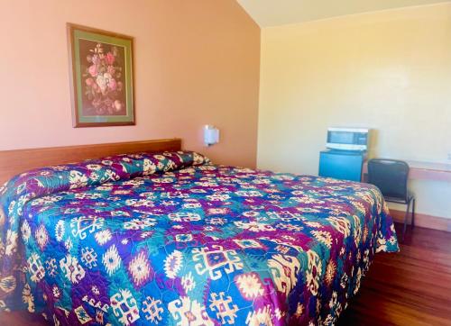 KingfisherPAYLESS INN的一间卧室配有一张带彩色床罩的床