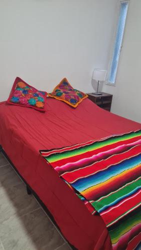 拉里奥哈Departamento cómodo的一张红色的床,上面有五颜六色的毯子