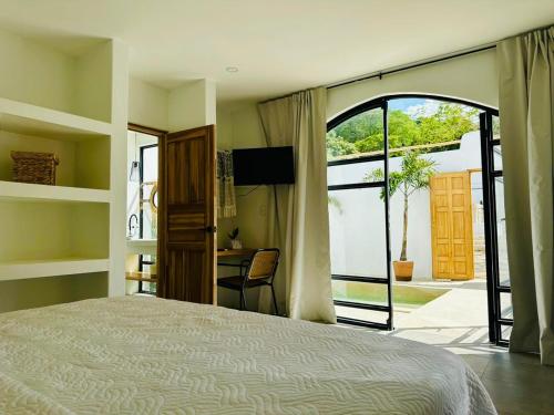 塔马林多Las Guapas Villas Tamarindo的一间卧室设有一张床和一个滑动玻璃门