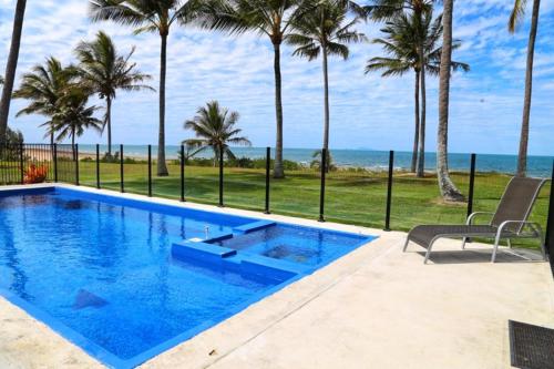 Sarina萨日娜海滩汽车旅馆的一座种植了棕榈树和大海的蓝色游泳池