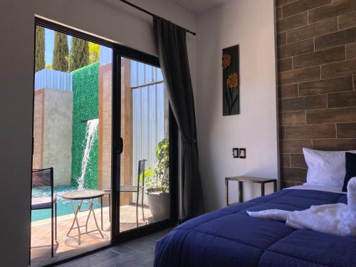 瓜达鲁佩镇Antia Valle de Guadalupe的一间卧室设有蓝色的床和滑动玻璃门