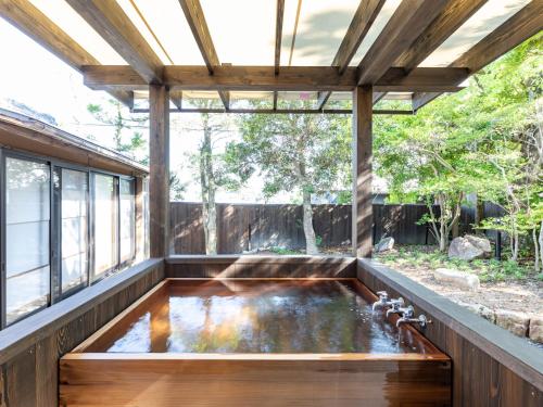 白滨Tabist Nanki Shirahama Ryokan Mantei的一座带凉棚的房子里的一个锦 ⁇ 池
