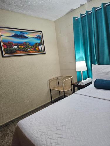 Nueva San SalvadorCat House的酒店客房,配有床、椅子和蓝色窗帘