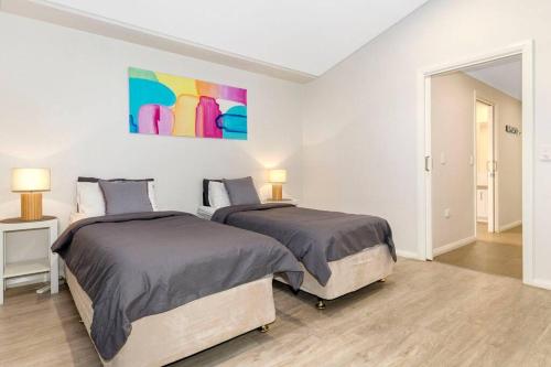 邓斯伯勒Aqua21 @ Cape Villas Dunsborough的一间卧室设有两张床,墙上挂着一幅画