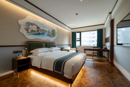 上海时光漫步S酒店(上海火车站苏州河店)的卧室配有一张大床,墙上挂有绘画作品