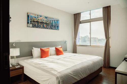 高雄华园大饭店草衙馆的卧室配有带橙色枕头的大型白色床