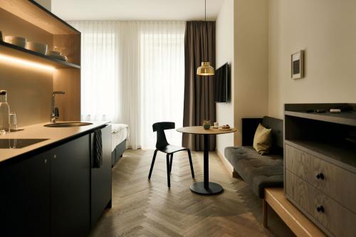 纽伦堡Melter Hotel & Apartments - a Neighborhood Hotel的厨房以及带桌子和沙发的客厅。