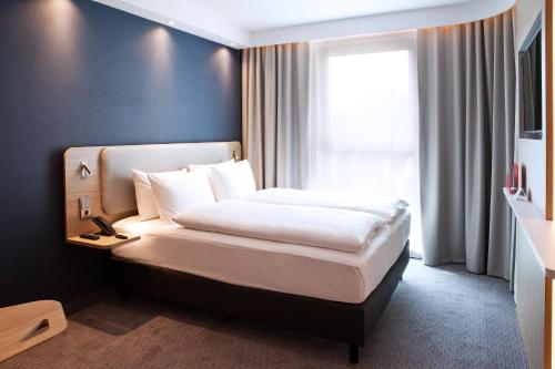 波鸿Holiday Inn Express Bochum, an IHG Hotel的一间卧室配有一张带白色床单的床和一扇窗户。