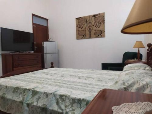 普拉亚Cozy Room in Plateau的一间卧室配有一张带桌子和一台电视的床。