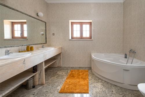 雷镇Quinta da Palhota的浴室设有2个水槽、浴缸和镜子