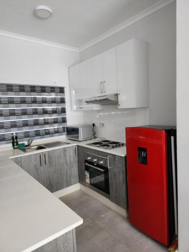 哈博罗内SaronaC102的厨房配有红色冰箱和白色橱柜