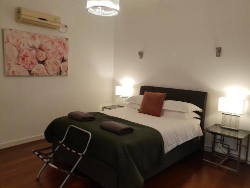 弗里曼特Leisurely Manor - spacious three bedroom home in Fremantle的一间卧室配有一张床、两张桌子和两盏灯。