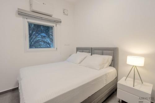 特拉维夫Luxury Shenkin 2BR by Airsuite的白色的卧室设有白色的床和窗户。