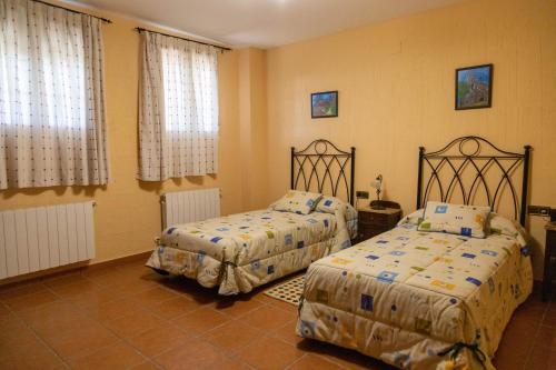 昆卡Casa Rural La Carbonera的一间卧室设有两张床和两个窗户。